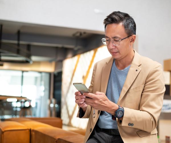 Middle-aged Asian businessman texting on his phone inside an office
