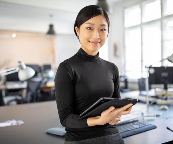 Businesswoman standing in office with a digital tablet.