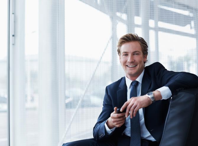 Businessman holding mobile phone while sitting in office