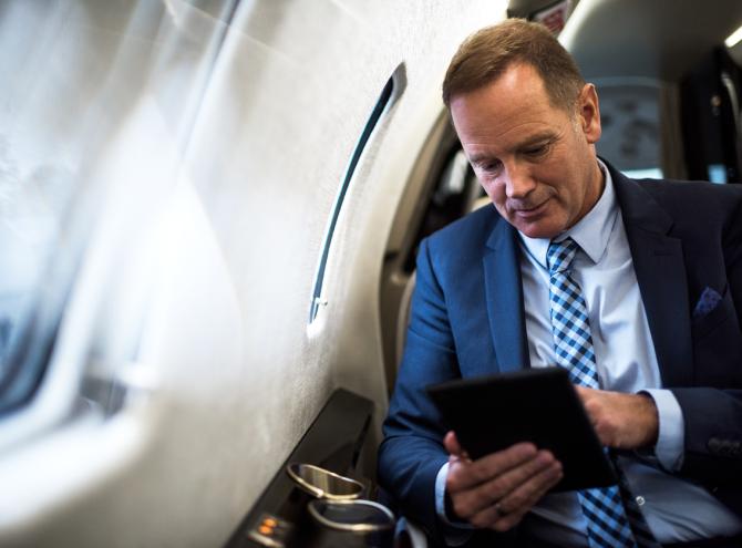 Businessman on airplane looking at tablet