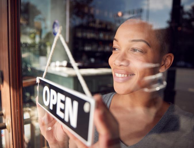 Businesswoman turning open sign on door of a shop