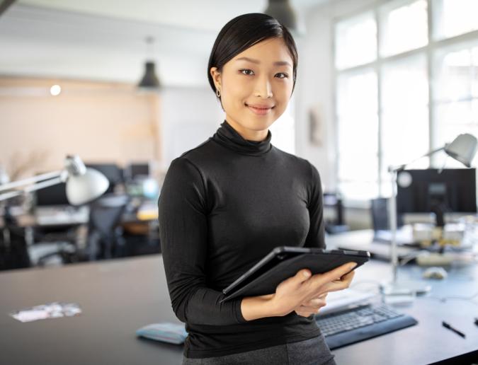 Businesswoman standing in office with a digital tablet.