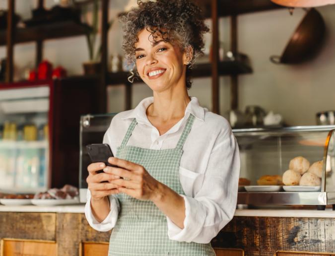 Small business owner using a smartphone in her cafe.